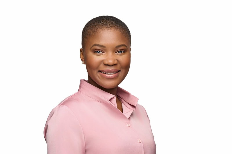 A professional AMCAS headshot photo of a smiling woman with short hair, wearing a soft pink shirt, against an isolated white background, exuding confidence and approachability.